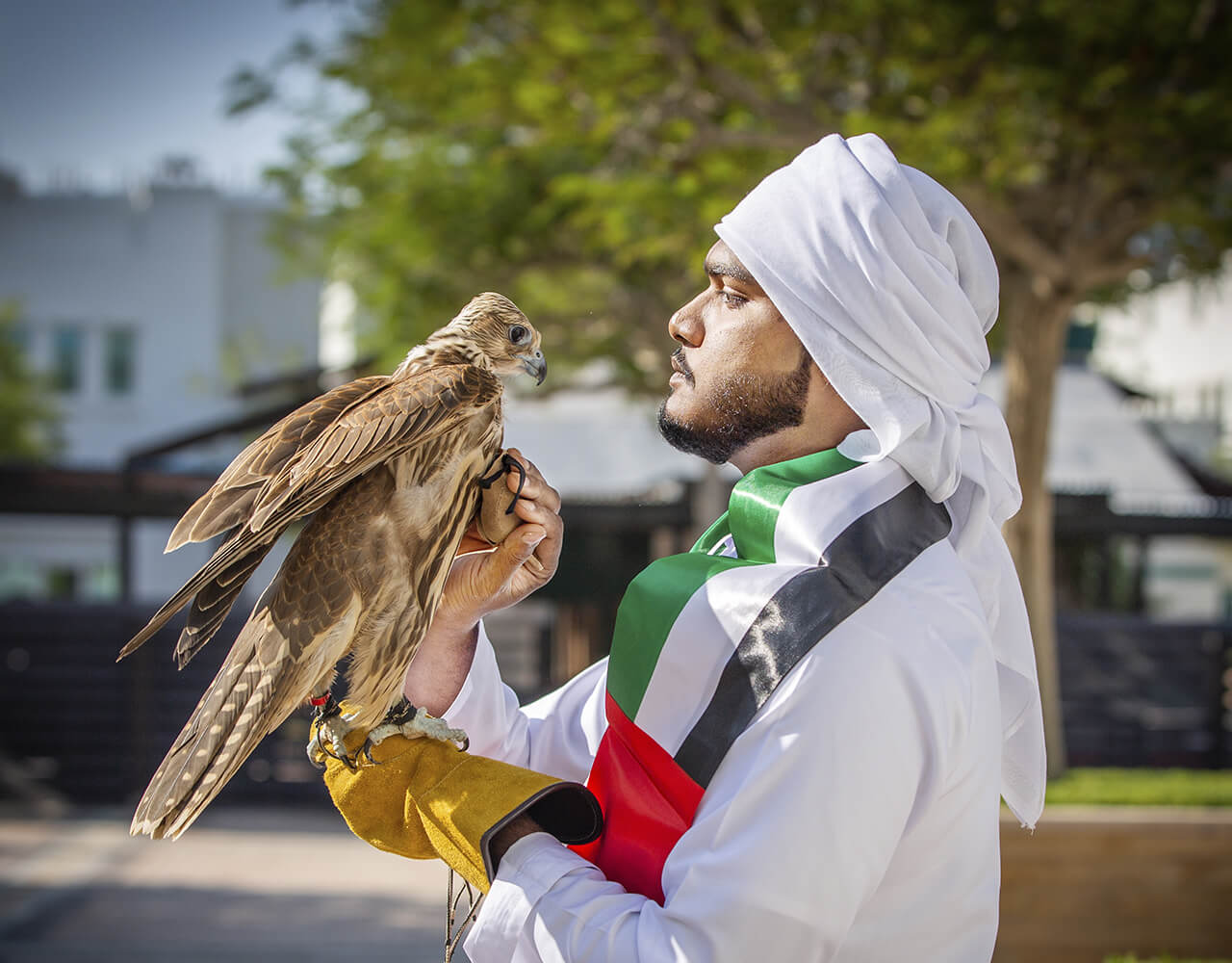 A man holding an eagle at Dubai International Academic City on Dubai Knowledge Park National Day event
