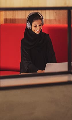  A woman with headphones happily working at one of our office spaces in Dubai Production City 